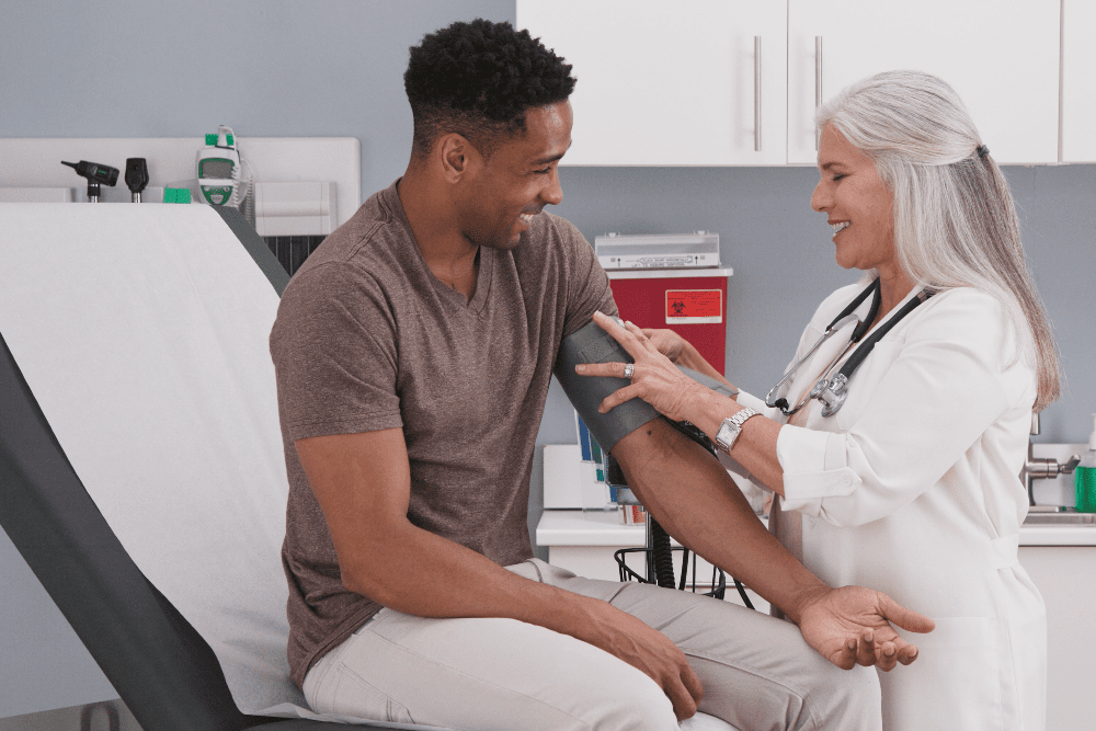 Mature White Female Physician Checking Male Patients Blood Pressure At Clinic