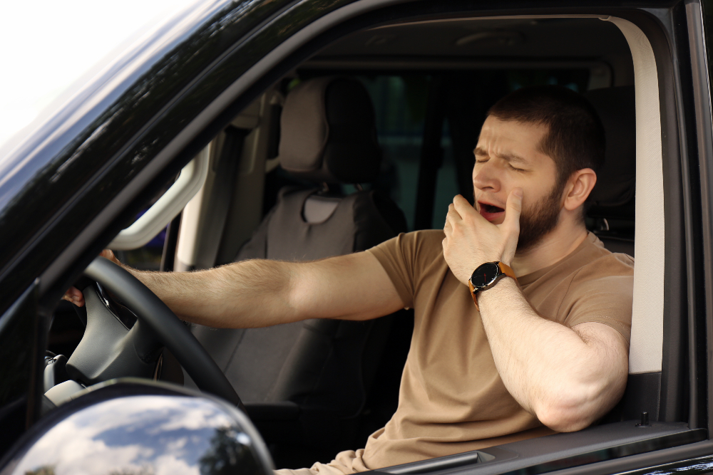 Tired-man-yawning-while-driving-his-modern-car
