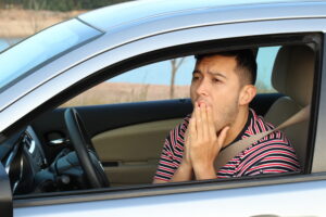 A terrified young male driver feeling guilty after an accident.